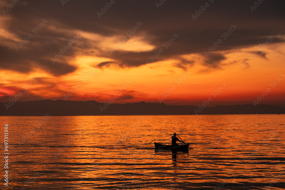 Fisherman in a dugout canoe at sunset in Lake Malawi in Cape Maclear, Malawi