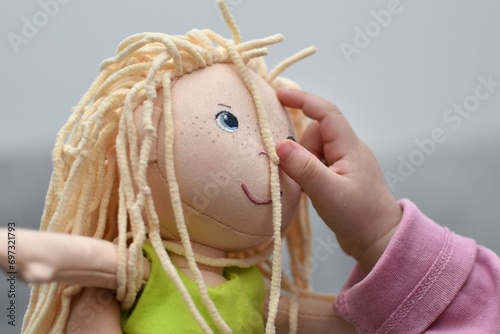 Fotografie baby  reaches out to a rag doll