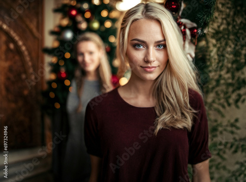 young women standing in front of a christmas tree at home, joyful smile, caucasian blond