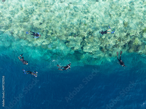 Snorkelers view a spectacular variety of corals and fish at the idyllic island of Midorang, Indonesia. The island is encircled by a reef flat the drops precipitously into Indonesia's deep ocean.  © ead72