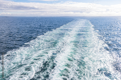 White waves and sea patterns in the blue ocean caused by a moving ferry in the Atlantic Ocean.
