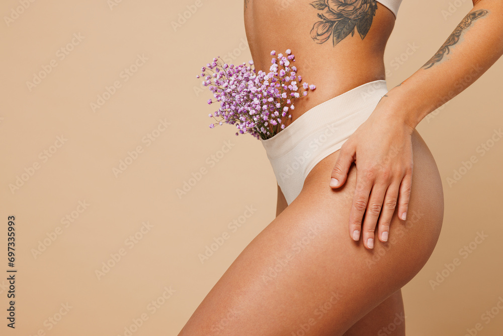 Close up cropped side view young nice lady woman with slim body perfect skin wears nude top bra lingerie stand with flowers in panties isolated on plain beige background. Lifestyle diet fit concept. - obrazy, fototapety, plakaty 