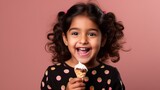 Ecstatic Indian girl with polka-dot dress enjoying a chocolate and vanilla ice cream cone.