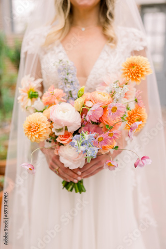 A close-up of a bride holding a soft wedding bouquet in pastels and soft pinks. 