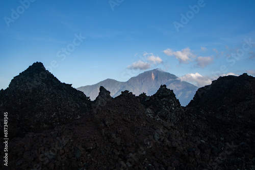 Landscape view of Mount Abang in the background through solidified black volcanic lava of an active volcano Batur, Bali island.