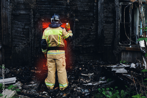 Concept call to rescue service banner. Portrait firefighter officer talking on radio walkie talkie with colleagues background wooden house in fire