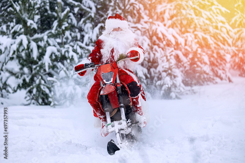Biker Santa Claus fast delivering Christmas gifts on snow bike, motorcycle ski background snow forest, sunlight