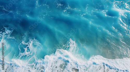 On a sunny day, a drone aerial view shows the beautiful waves and blue sea water of a summer seascape.