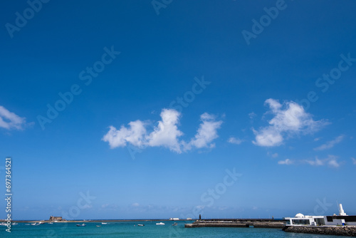 View of the Fermina islet. Turquoise blue water. Sky with big white clouds. Seascape. Lanzarote, Canary Islands, Spain. © Jess