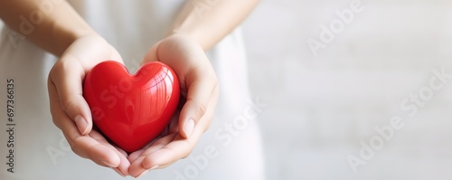 A person holding a red heart symbol on a white background