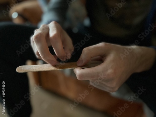 close-up of the hands of a young man sharpening his nails with a nail file made of natural materials © Irina