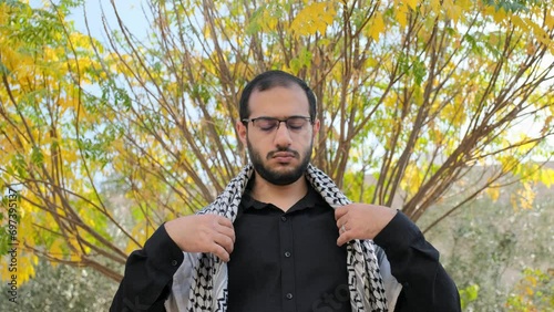 male wearing keffiyeh with tree in the background during autumn