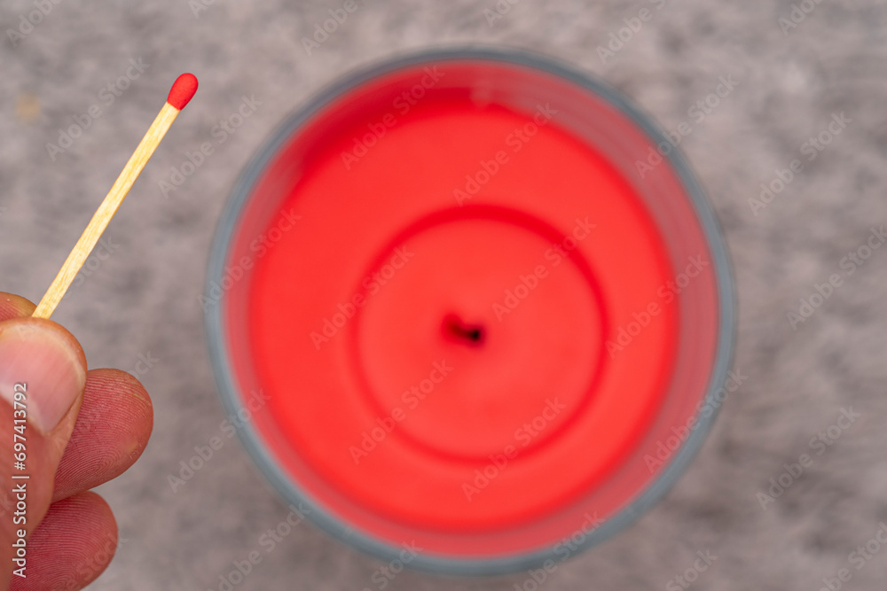 red wax candle with red headed matchstick approaching the wick. red wax candle with red headed matchstick approaching the wick.