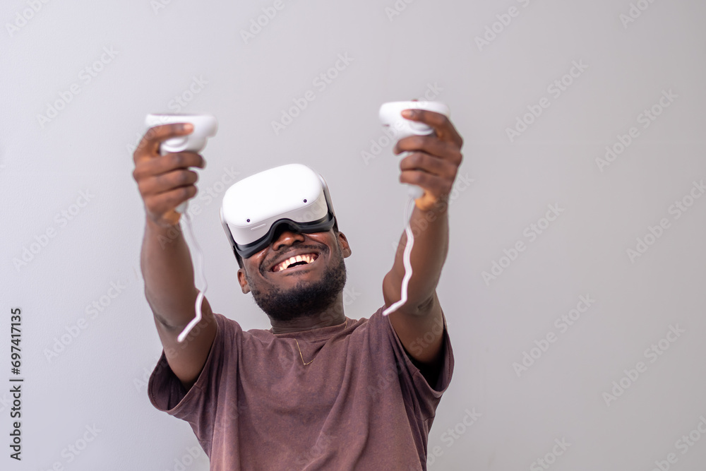 Excited Black Man wearing VR headset playing virtual reality game holding controllers. Man playing online games. VR gaming concept Excited Black Man wearing VR headset playing virtual reality game holding controllers. Man playing online games. VR gaming concept