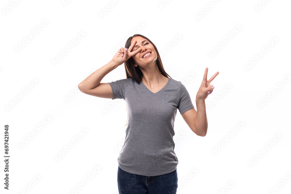 young cheerful european brunette woman dressed in a gray basic t-shirt on a white background with copy space young cheerful european brunette woman dressed in a gray basic t-shirt on a white background with copy space