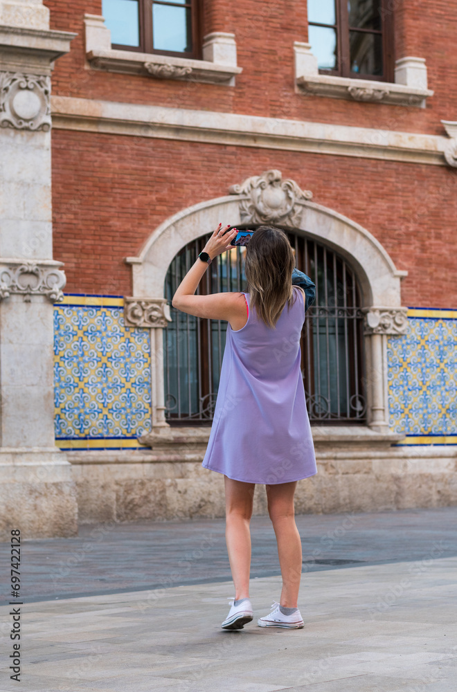 Valencia, Spain -September 22th, 2023: Girl photographs the central market building in Valencia. From the woman's cell phone you can see the detail of the Mercad Central facade.
