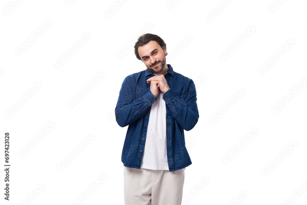 young handsome caucasian man with black hair is dressed in a blue shirt and light trousers on a white background young handsome caucasian man with black hair is dressed in a blue shirt and light trousers on a white background