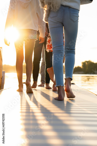 Family walking barefoot on a dock near a lake on summer vacation photo