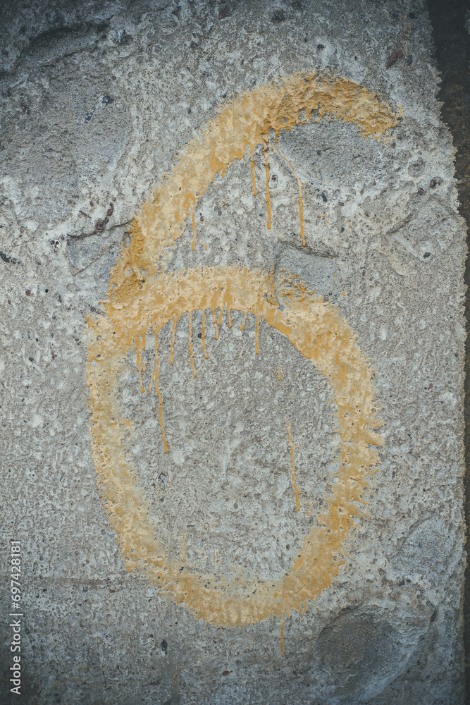 Yellow numbers on a concrete wall, number 6