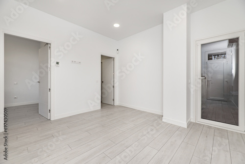 An empty room with gray parquet floors  white painted walls and white wooden access doors to other rooms