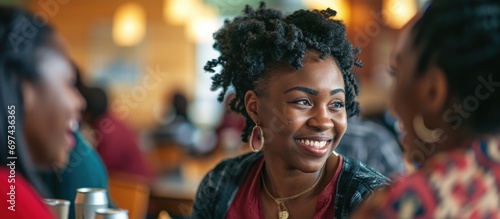 Black female student conversing with a joyful group of peers at university cafeteria. photo