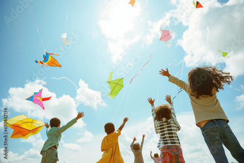 A diverse group of children enjoying a sunny and windy day flying kites outdoors, playing under the sun,welcoming spring photo