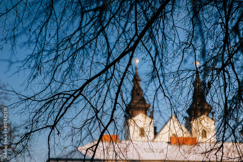 Dark, dense tree branches hide the two towers of the Assumption Cathedral against the blue sky in Lviv, Ukraine. Old City. photo