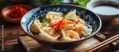 Popular Chinese cuisine includes wanton soup with shrimps dumplings, enjoyed with green pickled chili and soy sauce.
