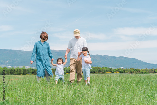 春・夏に公園・草原を歩く家族・ファミリー（子供・両親・移住・田舎暮らし） 