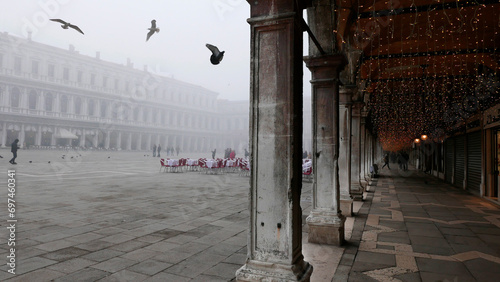 Venice in winter fog. Piazza San Marco, St Mark's Square, mostly empty apart from a few people, seagulls and pigeons.