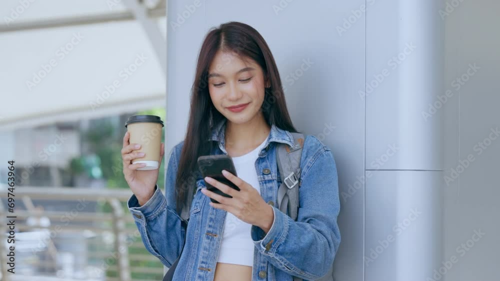 Young asian woman standing and using smartphone on the street Young asian woman standing and using smartphone on the street