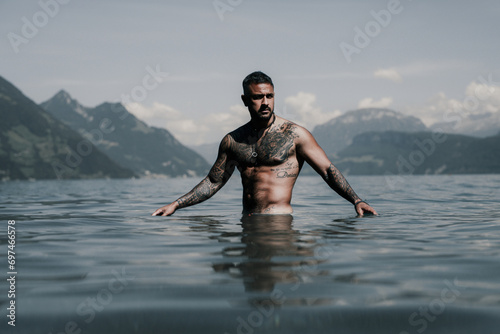 Muscular Hispanic man splashing water in lake. Attractive male sexy model in water. Handsome boy rest in Alps lake water. Sexy man naked torso in water. Man freedom lifestyle. Strong muscles guy.