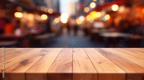 Empty wooden table top with a vibrant blurred background of city street lights and festive atmosphere.