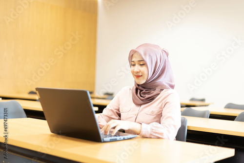 Asian Muslim woman wearing hijab working at office with documents on table, planning to analyze financial report, business plan, investing, financial concept and having fun at work