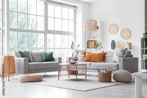 Interior of light living room with grey sofas, coffee table and wicker poufs photo