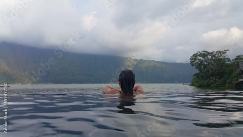 Hot springs in Bali are amazing natural places with thermal pools in open air. Hot springs near Lake Batur and woman enjoying relaxation photo