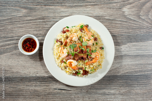 A top down view of a plate of fried rice, featuring pork belly and shrimp.