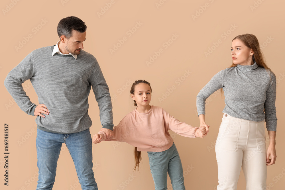 Sad little girl with her divorced parents on beige background Sad little girl with her divorced parents on beige background