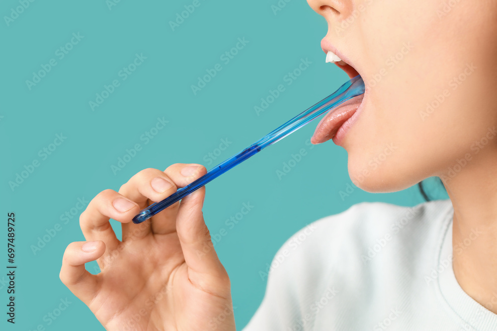 Young woman with tongue scraper on blue background - obrazy, fototapety, plakaty 