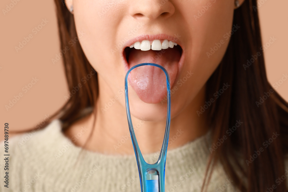 Young woman with tongue scraper on brown background Young woman with tongue scraper on brown background