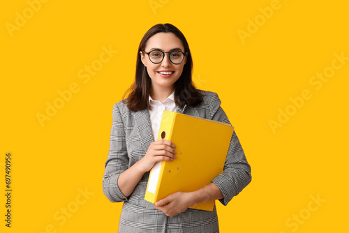 Young businesswoman in eyeglasses with document folders on yellow background