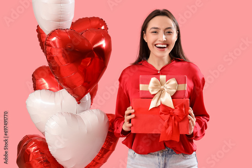 Young woman with gifts and heart-shaped balloons on pink background. Valentine's Day celebration © Pixel-Shot