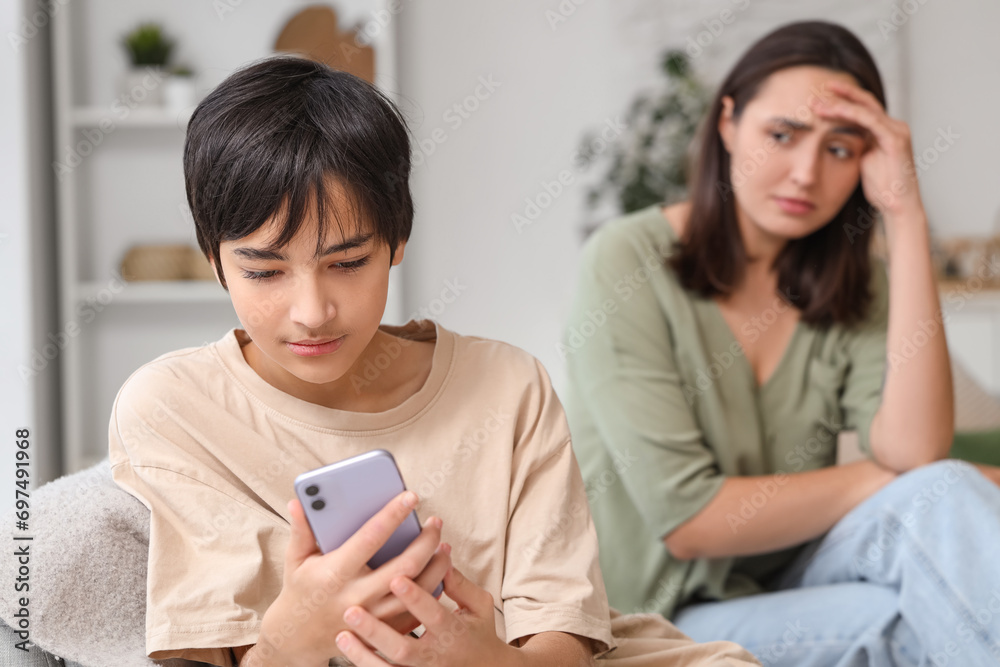 Teenage boy using mobile phone and his upset mother at home. Family problem concept Teenage boy using mobile phone and his upset mother at home. Family problem concept
