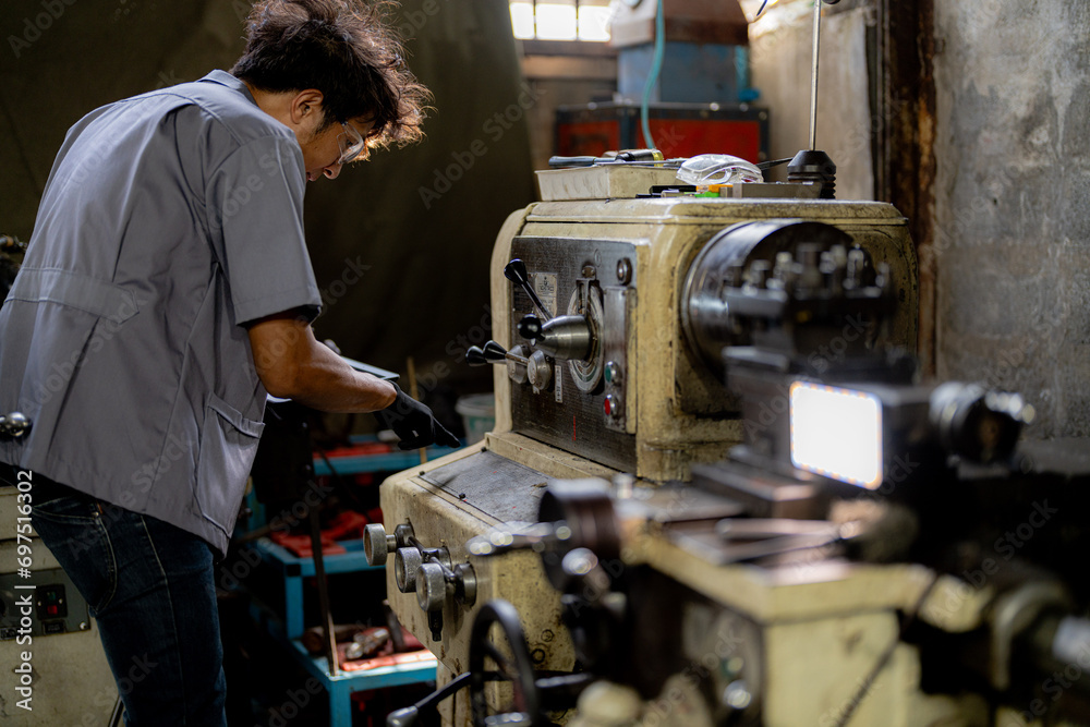 Fototapeta premium Asian worker in production plant drilling at machine. Professional worker near drilling machine on factory. finishing metal working internal steel surface on lathe grinder machine with flying sparks.