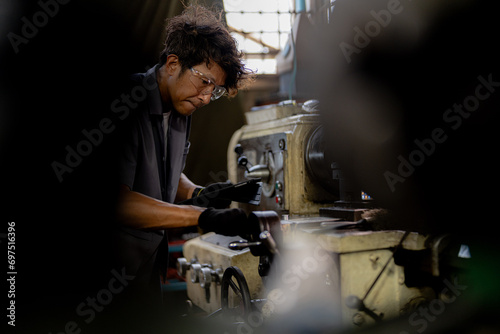 Asian worker in production plant drilling at machine. Professional worker near drilling machine on factory. finishing metal working internal steel surface on lathe grinder machine with flying sparks.