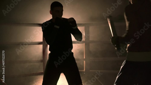 A male boxing trainer gives lessons and trains a young boxer in the ring. photo