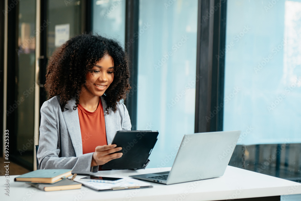Young woman typing on tablet and laptop while sitting at the working in office