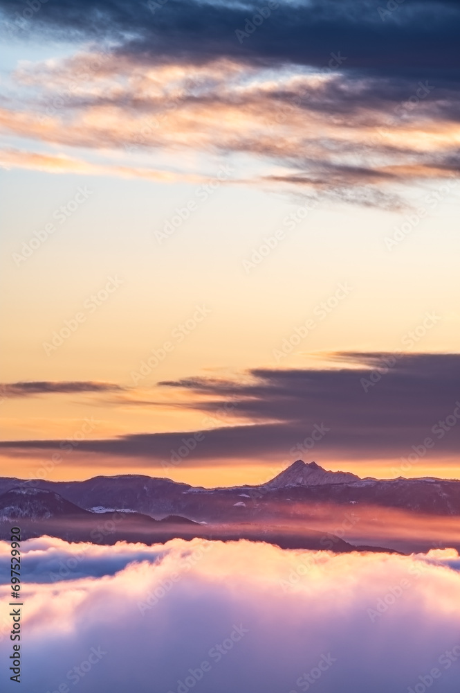 朝焼けの空の下、雲の向こうに遠くの山の稜線。