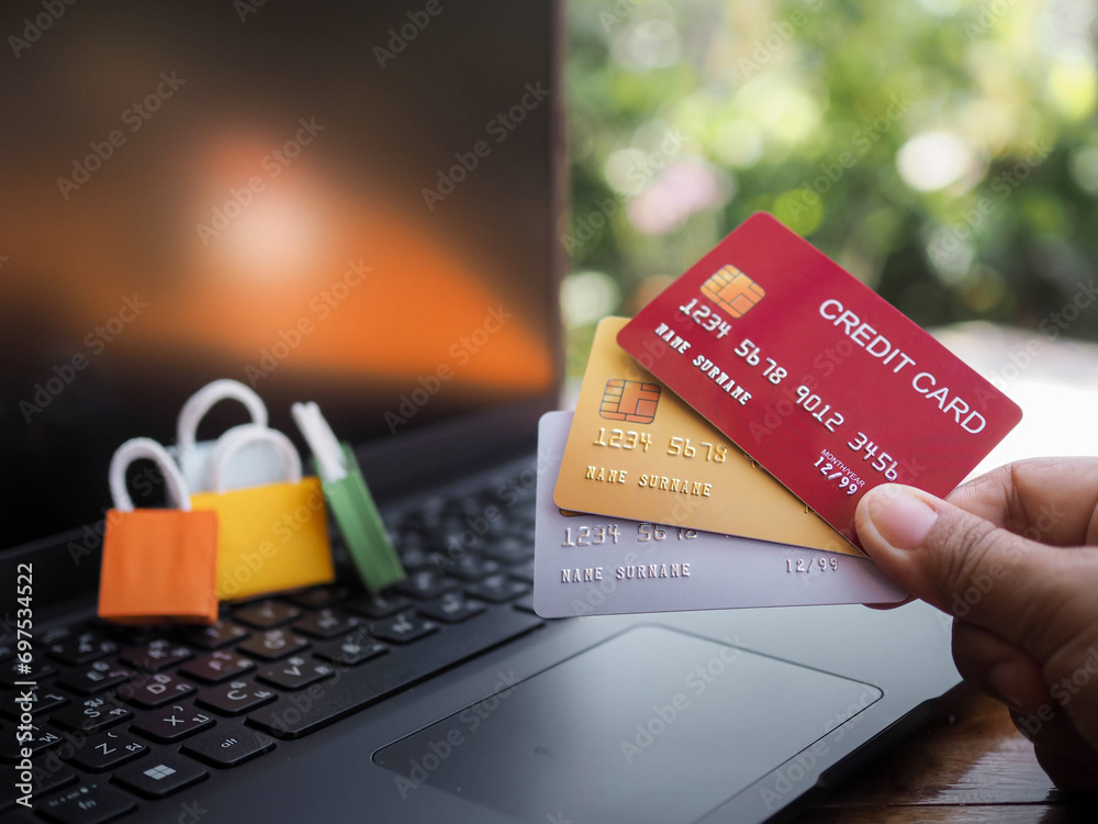 Woman hand holding credit cards and shopping bags on a laptop keyboard. Concepts about online shopping that offers home delivery