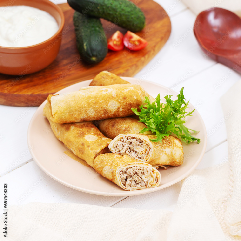 Pancakes with meat on a plate, lunch, on a light wooden background Pancakes with meat on a plate, lunch, on a light wooden background